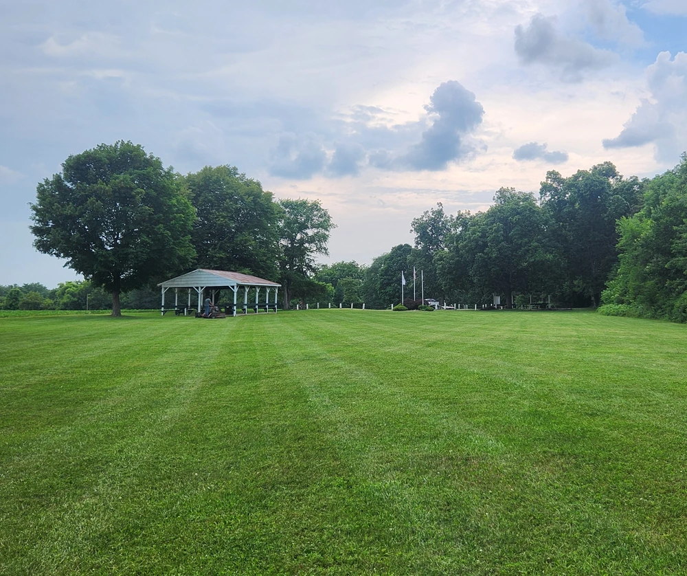Wide open lawn maintained after winter thaw using proper lawn maintenance techniques to prevent soggy grass areas.
