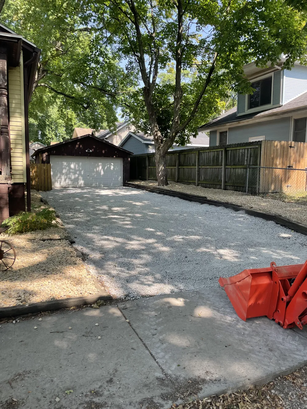 Gravel patios and driveway under trees, inspecting borders and base for winter washouts and settling.