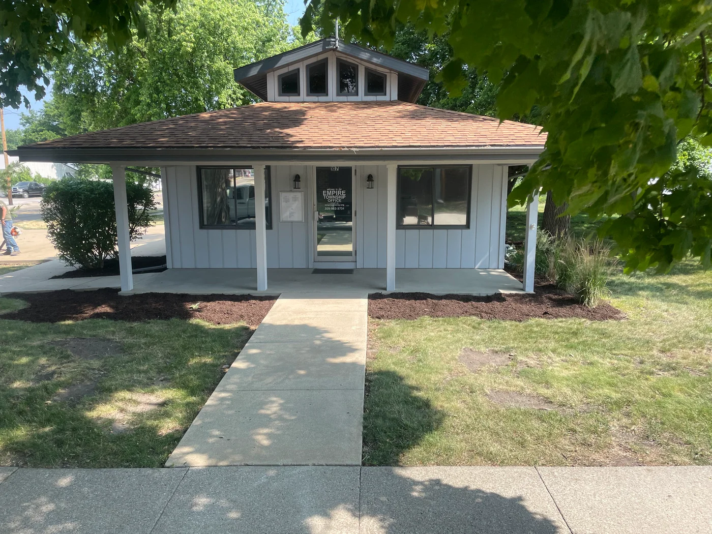 Light blue cottage-style building with a straight walkway through dark mulch landscaping beds.