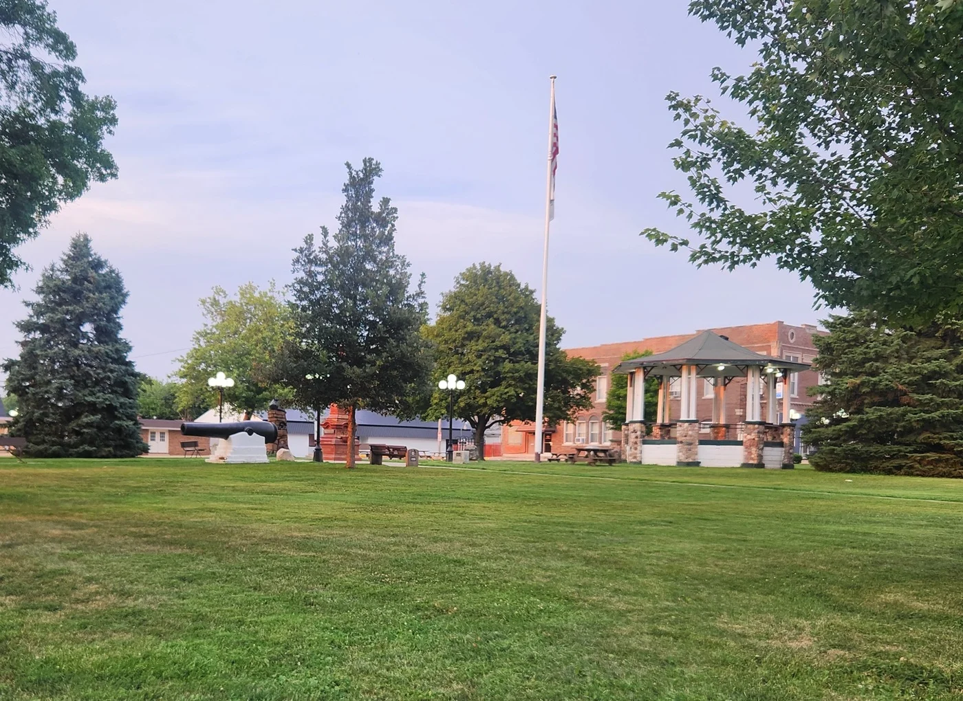 Wide green lawn with mature trees in front of a brick community building.